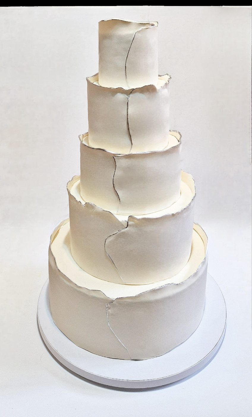 Five-tier white wedding cake with torn fondant edges